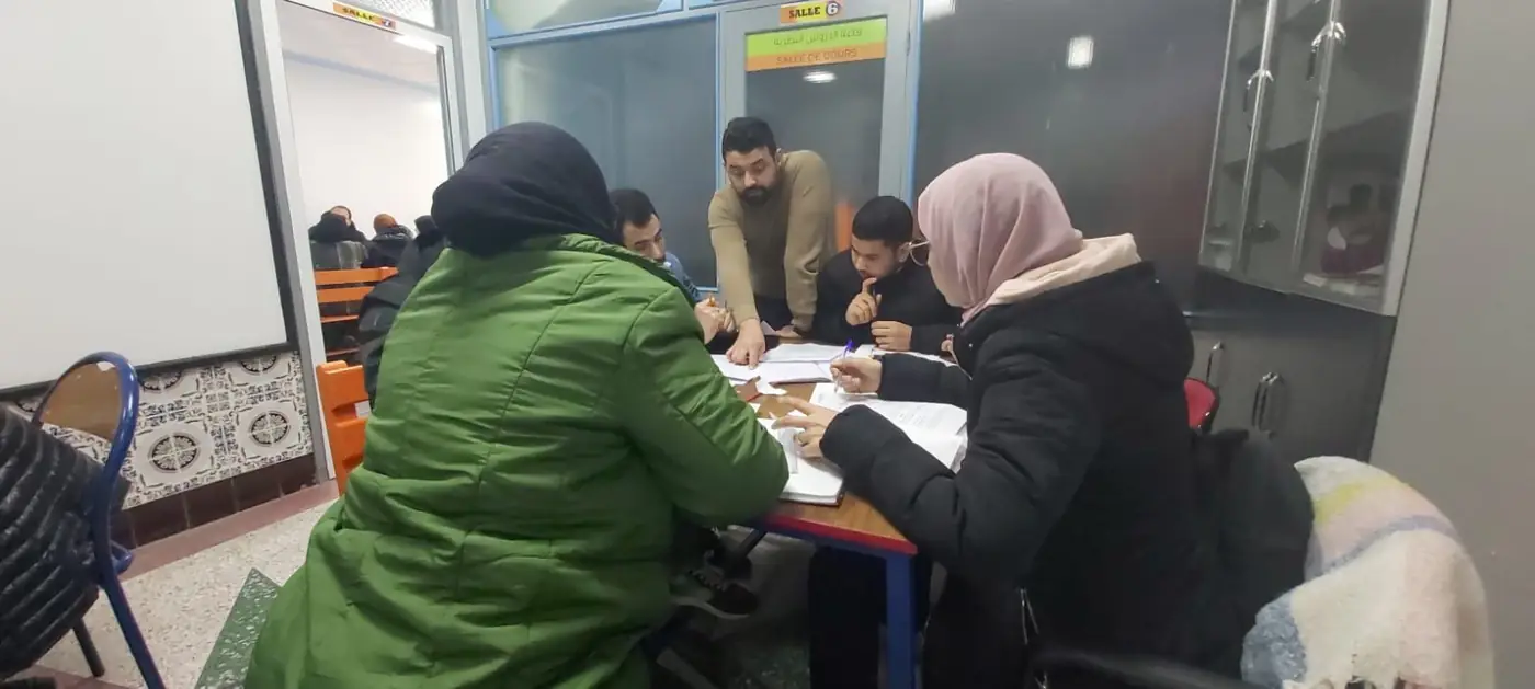 Un formateur accompagne un groupe de stagiaires en salle de cours